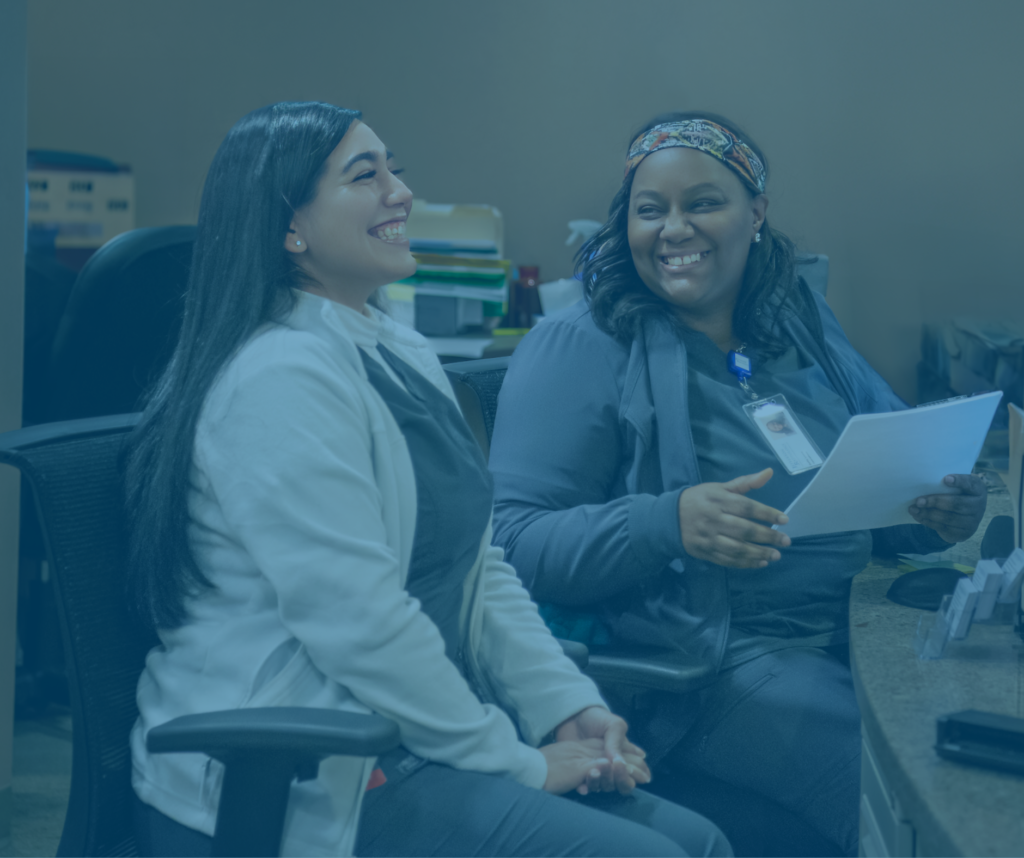 two front desk workers smiling and laughing together